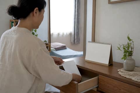 밝은 방에서 서랍에 서류를 넣어 정리하는 사람과 탁상 달력